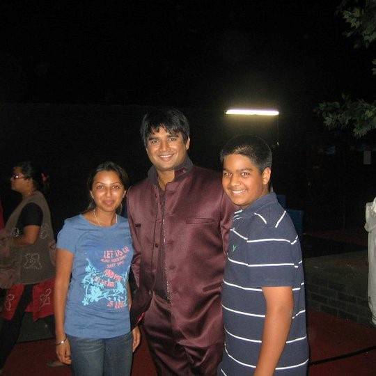 Creative director and founder of Dance Expression Studio, Neha, R. Madhavan, renowned Bollywood actor, and Prashant Karam, marketing manager at Dance Expression smiling for a photo on a film set during the evening.
