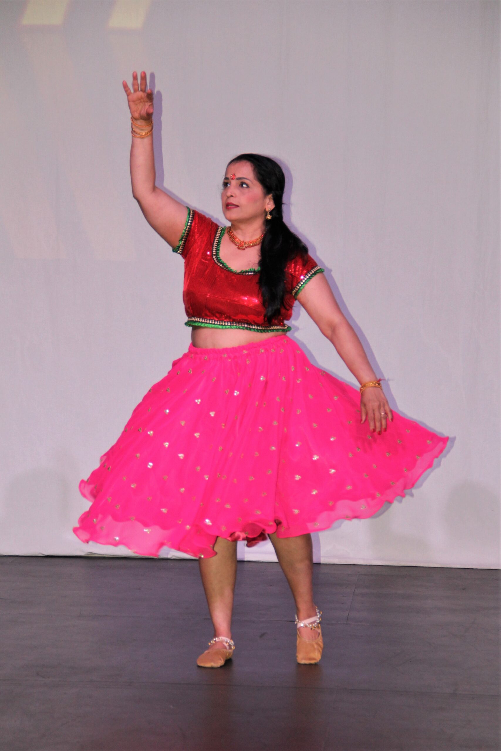 Dance Expression student, Jayshri Venkataraman elegantly performing at the 2023 Dance Expression showcase in Ajax, wearing a vibrant pink and red dance costume.