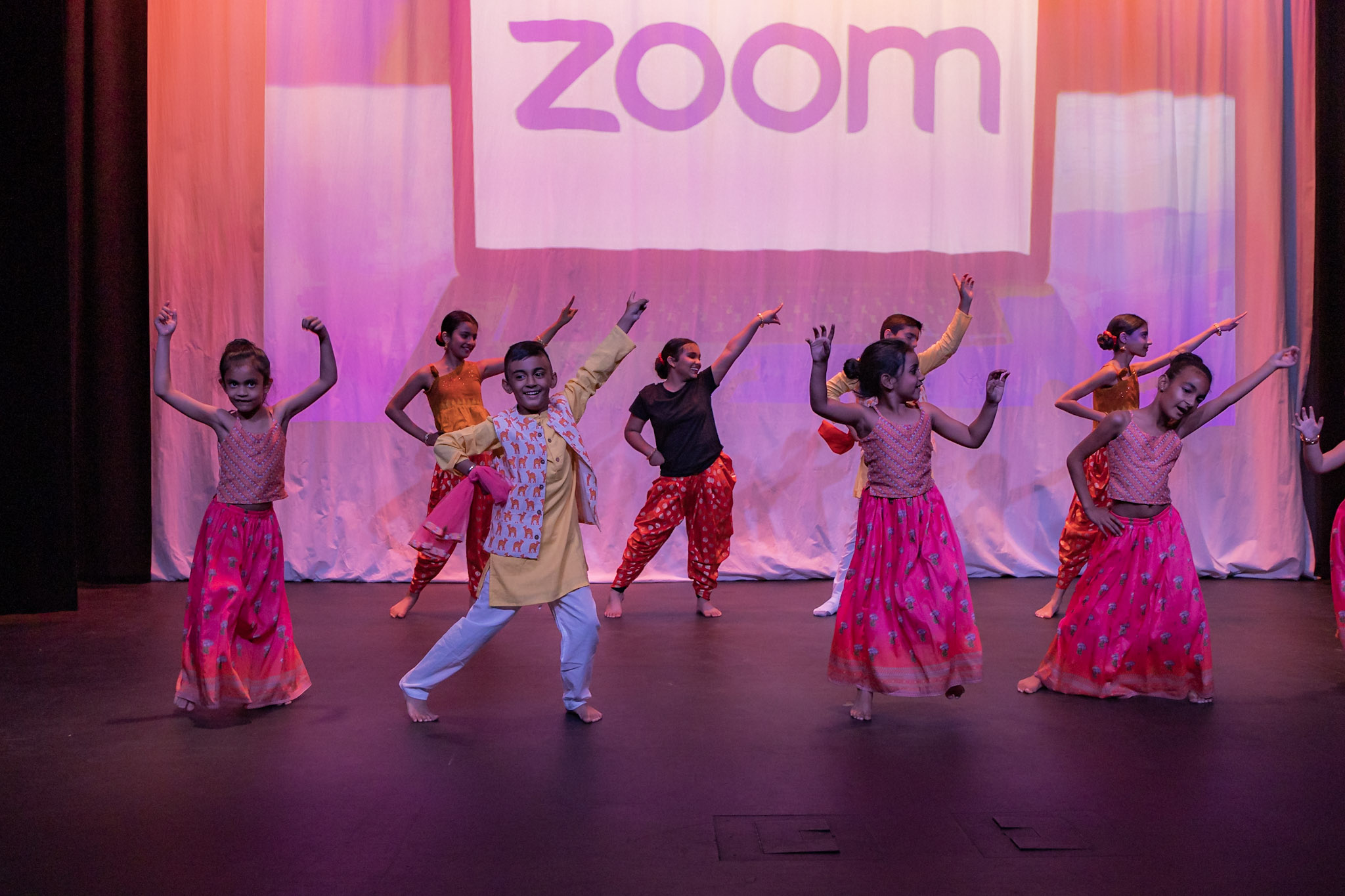 Dance Expression students perform a dynamic dance routine at the annual Dance Expression showcase in Ajax, Ontario, 2022, with a backdrop displaying the Zoom logo